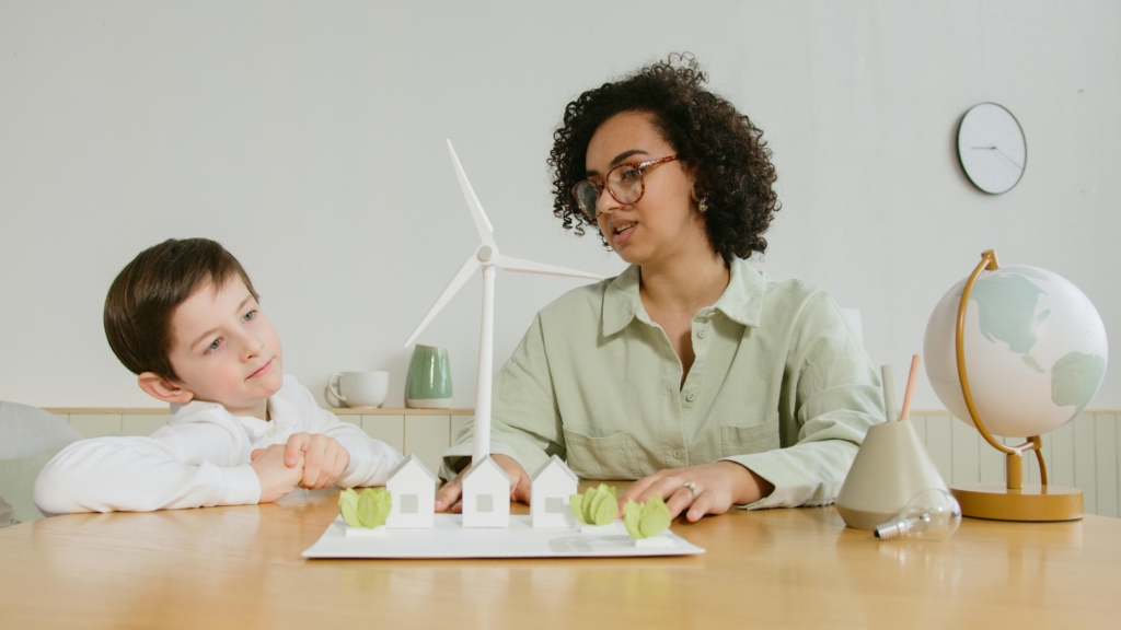 mujer y niño trabajando sobre una maqueta de una ciudad alimentada por energía sustentable.